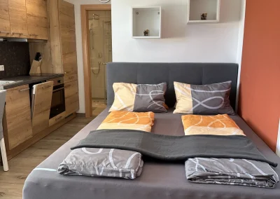 Boxspringbett und Küchenzeile in einem modernen Studio-Apartment am Gut Maierleben.