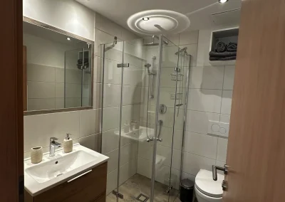 Helles Badezimmer mit bodennaher Dusche, Waschbecken und WC im Appartement Rupert.